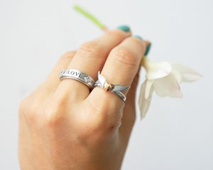 Hand wearing Lavaggi wings of love ring and holding white flower